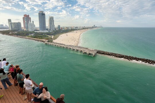 Miami, United States - 16 March 2026: View of the vibrant Miami skyline towering over South Beach, where turquoise waters meet sandy shores and a bustling pier under a dynamic sky.