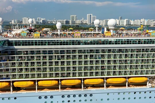Miami, United States - 16 March 2026: View of a majestic cruise ship's vibrant upper decks teeming with passengers against the gleaming Miami skyline.