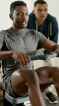 Rower inhaling initiating stroke on erg driving legs pulling handle, coach guiding form for fitness