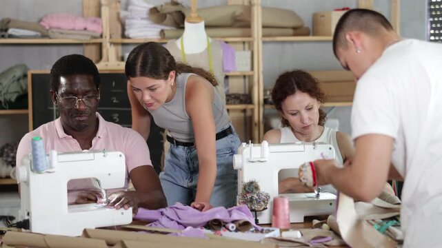 Polite middle-aged man instructor controlling students using sewing-machine at dressmaking courses