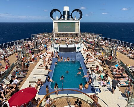 Nassau, The Bahamas - 19 March 2026: View of a vibrant cruise ship deck teeming with sunbathers enjoying the azure pool and endless ocean under a brilliant sky.