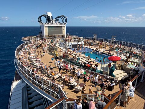 Nassau, The Bahamas - 19 March 2026: View of a vibrant cruise ship deck teeming with sunbathers enjoying the sparkling pool and vast blue ocean under a brilliant sky.