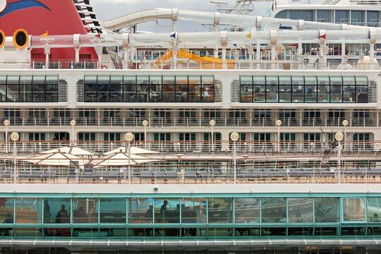 Nassau, The Bahamas - 18 March 2026: View of a massive cruise ship's multi-deck structure, showcasing vibrant red and white against reflective glass and thrilling water slides.