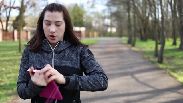 Woman tracking fitness progress during run checking smartwatch and writing results in notebook outdoor workout cardio training healthy lifestyle sport routine focus