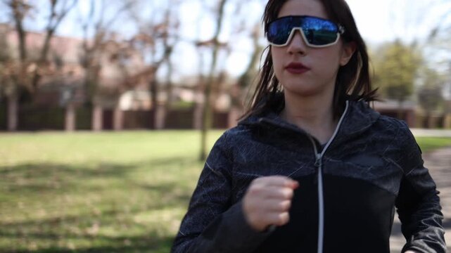 Woman maintains steady run through green park focusing on rhythm and breathing building stamina and mental resilience through consistent outdoor training