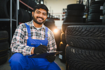 Indian auto mechanic inspecting tires in workshop © Serhii