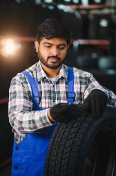 Indian man mechanic checking new car tire in workshop