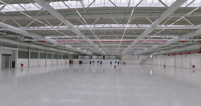 Wide view of an empty warehouse interior with polished floor reflecting overhead lights