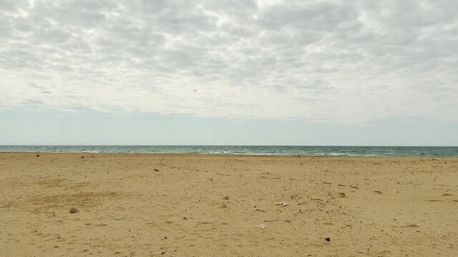 A wide expanse of textured clouds hangs over the quiet shoreline. The stillness of the sea and the empty sand create a deep sense of solitude and peace. It feels like a moment of pure, refreshing calm