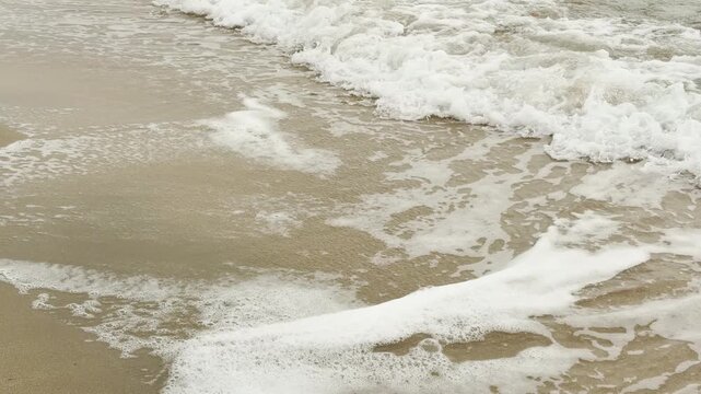 Gentle ocean waves break into white foam against the smooth golden sand. The vast horizon creates a lonely, peaceful feeling of endless space. This scene feels calm, refreshing, and deeply serene.