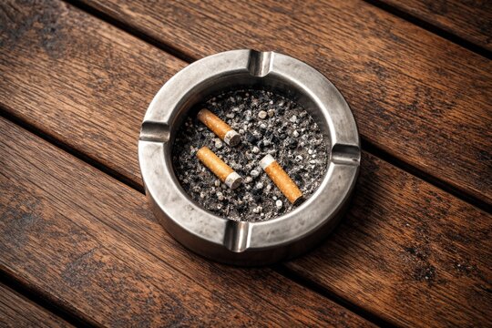 Aerial shot showing a metal ashtray on a textured wooden table