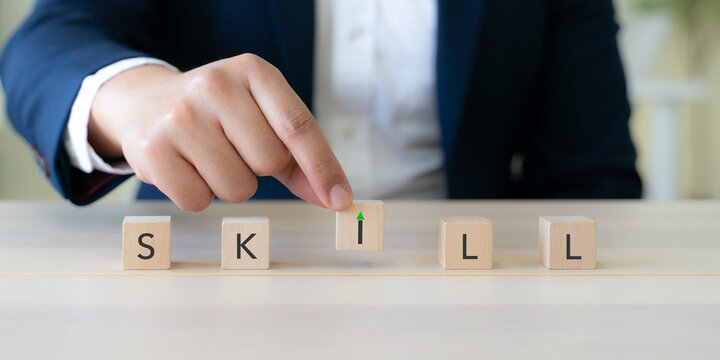 Upskilling and Skill Enhancement Concept. A hand lifts the &ldquo;I&rdquo; block in SKILL, forming a gap with an upward arrow, symbolizing upskilling, progress and continuous improvement in workforce capability.