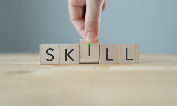 Upskilling and Skill Enhancement Concept. A hand lifts the &ldquo;I&rdquo; block in SKILL, forming a gap with an upward arrow, symbolizing upskilling, progress and continuous improvement in workforce capability.