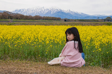 Fototapeta premium Girl in Yellow Flower Field with Mountains