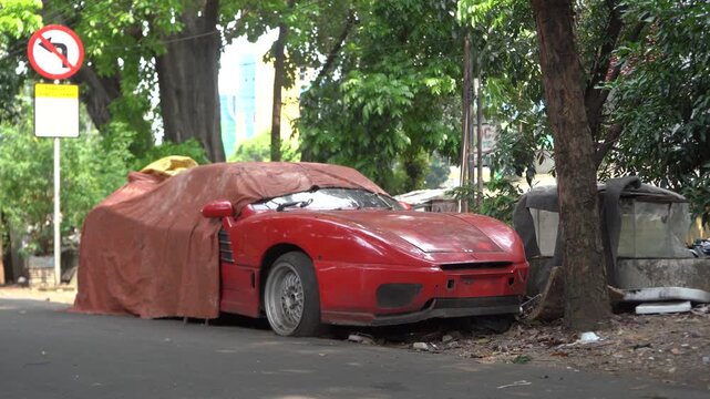 A Red Car Covered In A Tarp Is Parked On The Side Of The Road