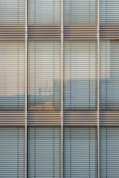 Modern architecture facade with office corporate finance pattern and symmetry seen in glass windows behind blinds creating clean geometric texture