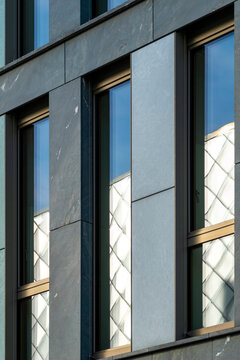 Modern architecture facade shows office corporate finance pattern and symmetry in glass windows with dark cladding creating minimalist business exterior