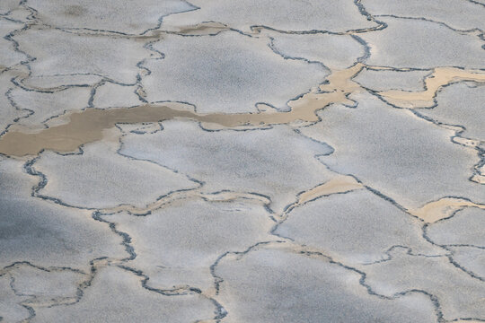 View of cracked earth patterns resembling a mosaic of dry land, with winding streams of light brown water carving through the parched landscape, Tallinn, Estonia.