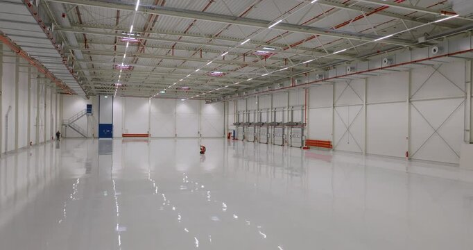 Panning view of a large empty industrial building interior with high steel roof structure