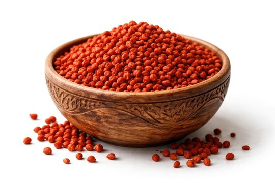 Hand carved bowl holding bright annatto seeds on a crisp white background