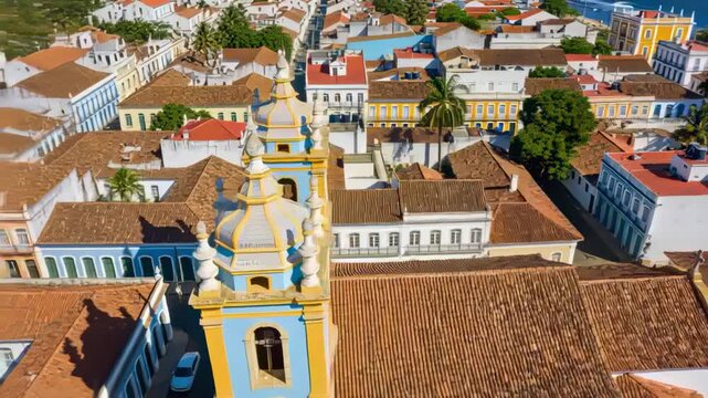 Pulling back camera revealing blue-yellow baroque church in coastal town, exposing palm shore
