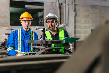 Fototapeta premium Factory Technicians Performing Heavy Machine Maintenance in Traditional Metal Workshop