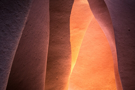 View of sculpted sandstone walls glow with warm, ethereal light, casting soft shadows and revealing intricate textures in Escalante, Utah, United States.
