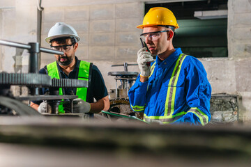 Fototapeta premium Factory Technicians Performing Heavy Machine Maintenance in Traditional Metal Workshop