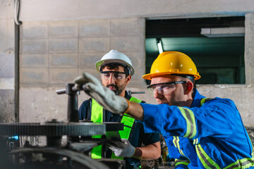 Fototapeta premium Factory Technicians Performing Heavy Machine Maintenance in Traditional Metal Workshop