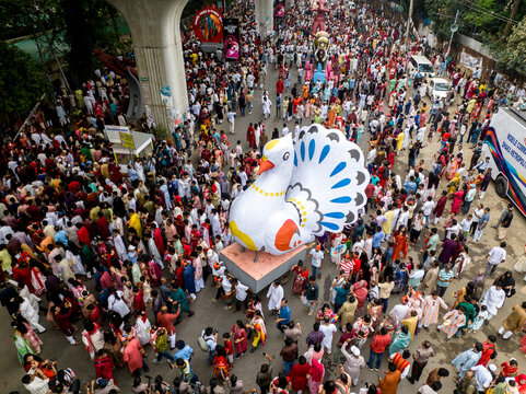 Dhaka, Bangladesh - 13 April 2026: Aerial view of a vibrant sea of people surrounding a colossal, colorful bird float under an elevated structure.