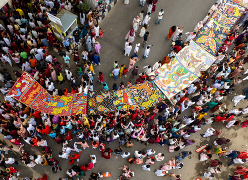 Dhaka, Bangladesh - 13 April 2026: Aerial view of a lively cultural procession, with a dense crowd admiring vibrant traditional artworks on a grey street.