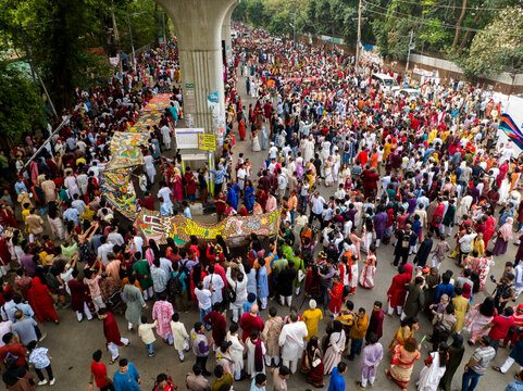 Dhaka, Bangladesh - 13 April 2026: Aerial view of a vibrant, dense crowd in colorful attire, a river of humanity flowing past a massive concrete pillar.