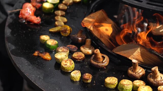 Grilling vegetables, meat, and fish at a fair. Close-up of delicious vegetables grilling over a fire, preparing food for sale at the fair.
