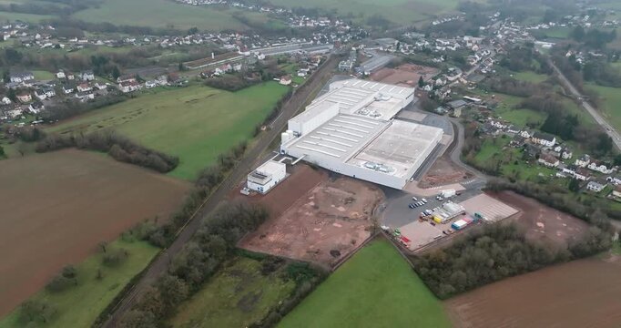 High angle aerial view of a massive white distribution center with numerous loading docks and green surroundings