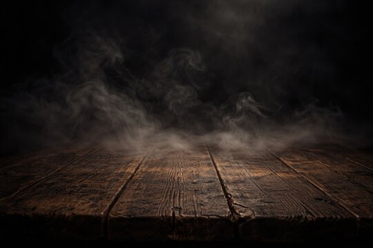 Dark backdrop with smoke hovering above an old wooden tabletop