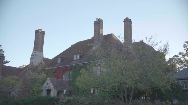 Exterior view of a historic ivy-covered mansion at Jens Jensen Gardens with tall chimneys in autumn light.