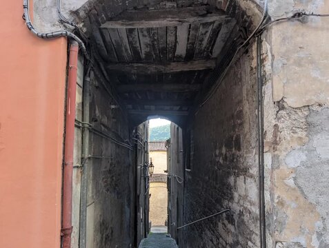 Vicolo stretto tra edifici storici in pietra, con archi, finestre e pavimentazione in ciottoli. Una scena suggestiva che cattura l&rsquo;atmosfera autentica di un borgo antico italiano