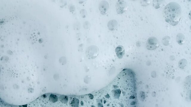 Bubbles of white soap foam. Moving Soap foam popping bubble on a blue backdrop. Soap sud macro structure. Clean, cleaning concept, laundry, shower. . High quality 4k footage