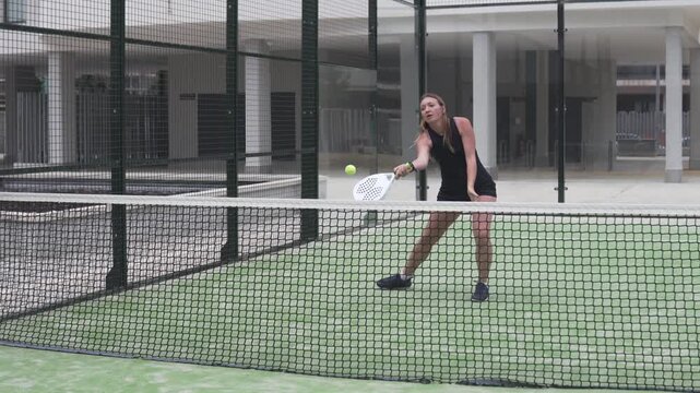 Woman playing padl on court in her urbanization in Spain,
