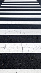 Fototapeta premium A highangle view of a pedestrian crosswalk featuring alternating white paint stripes on weathered asphalt