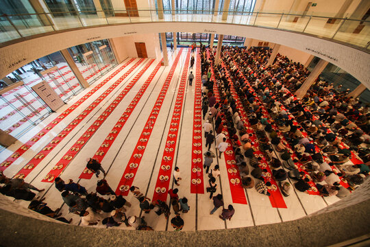 Dhaka, Bangladesh - 19 March 2025: View of a grand prayer hall, where rows of worshippers contrast sharply with vibrant red mats and light floors, under soaring architecture.