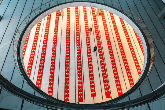 Dhaka, Bangladesh - 19 March 2025: View of a vibrant red and white patterned floor, seen from a high circular vantage point, with two distant figures.