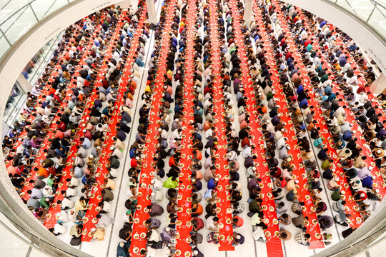 Dhaka, Bangladesh - 19 March 2025: View of a vast assembly of people, their varied attire a vibrant mosaic against the striking crimson expanse of meticulously arranged dining tables.