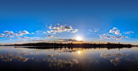 Obraz premium A panoramic dome of cumulus clouds. An arch of magical purple sunset with yellow and orange reflections from the sun is reflected calm waves river. A calming evening spectacle. Pink flakes of steam.