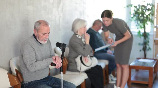 Elderly man and woman in casual clothes waiting for his turn on chair in reception. High quality 4k footage