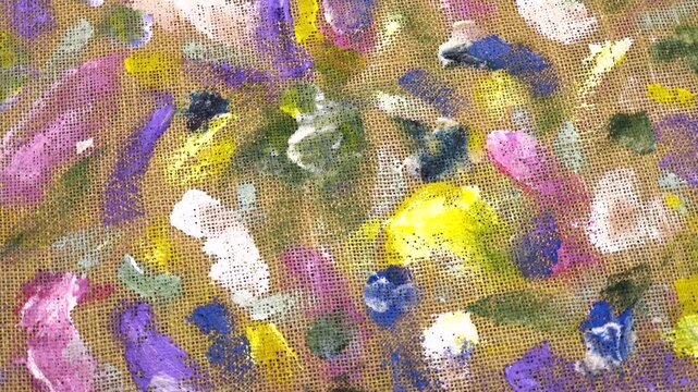 Various multi-colored spots of different shapes from paint brushes with gouache and acrylic paint on the beige burlap fabric, abstract background, top view