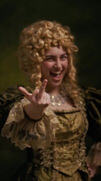 Vertical portrait of Caucasian noblewoman in curly wig and ornate baroque dress laughing while showing middle finger gesture toward camera