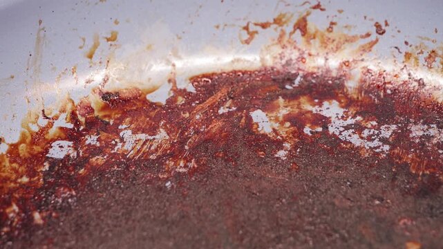 A frying pan sits on the stove after cooking, showing burnt food stuck to the surface. The heat left stubborn marks, making the pan look messy and in need of a good clean. High quality 4k footage