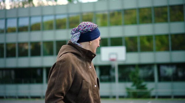cancer survivor standing outdoors near school building after chemotherapy expressing recovery independence strength and return to normal life after difficult treatment journey