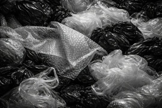 Black and white composition of mixed plastic bag types and bubble wrap in recycling heap